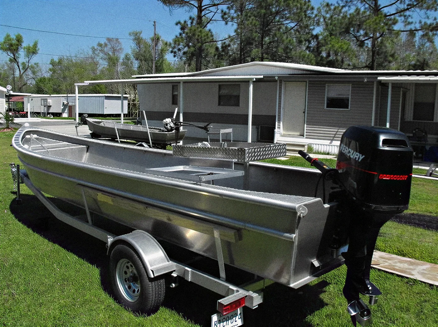 Finished EMF aluminum boat with center console and outboard on a trailer outside the shop